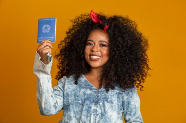 mulher segurando carteira de trabalho representando o que fazer com o primeiro salário